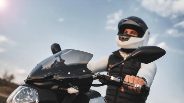 портрет молодого человека, ехав на мотоцикле и одетого в шлем. - motorcycle handlebar road riding стоковые фото и изображения