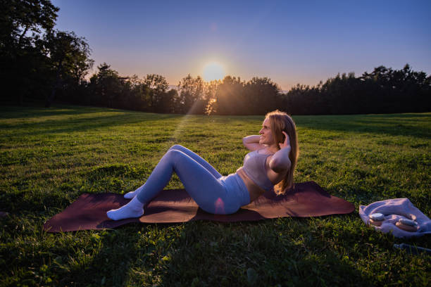 atleta feminina exercitando sit-ups no parque - pilates women sit ups yoga - fotografias e filmes do acervo