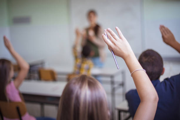 istock Middle group of students raising their arms to answer the question. 1310413363