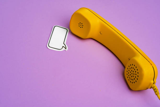istock Yellow landline phone with speech bubble on purple background 1310415123