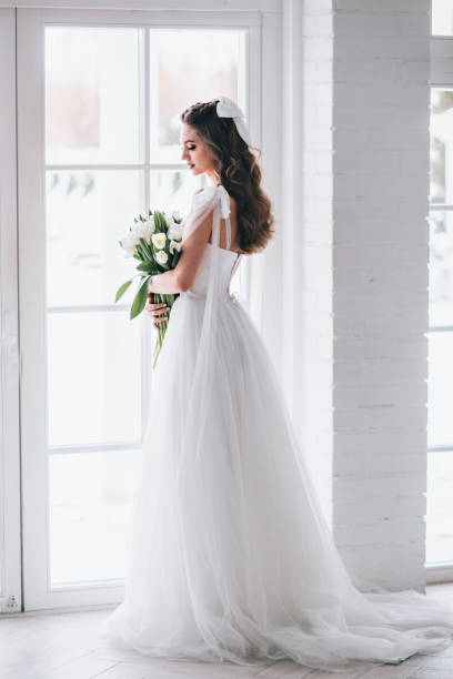 istock Beautiful brunette woman as bride with wedding bouquet in studio 1310415475