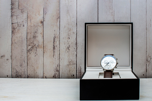expensive wristwatch in a box against shabby lumber wall with copy space