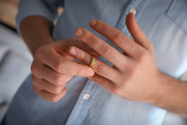 istock Man taking off wedding ring on blurred background, closeup. Divorce concept 1310415715
