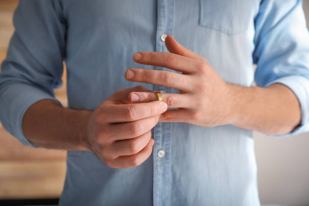 istock Man taking off wedding ring on blurred background, closeup. Divorce concept 1310415780