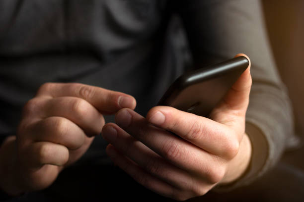 istock Young businessman holding and using smart phone dialing touch screen cell phone in office. business, lifestyle, technology and social media network concept 1310418483