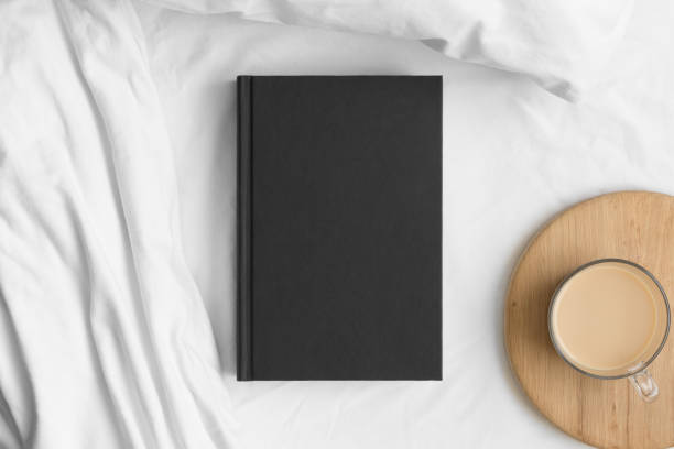 istock Black book mockup with a cup of coffee on a bed. 1310418616