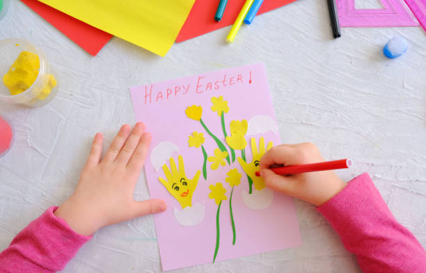 istock Child making card with Easter funny eggs and flowers  from colorful paper. Handmade. 1310420552