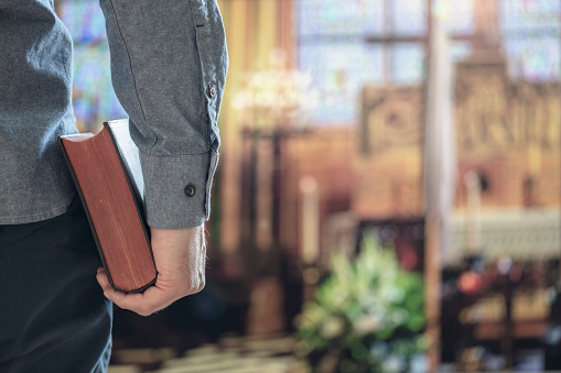 Hombre sosteniendo santa biblia en iglesia con alter en el fondo photo