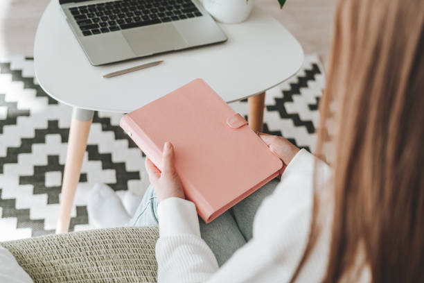 Woman writes in notebook with laptop