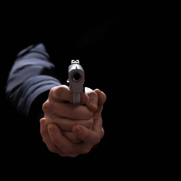 istock Hands threaten with weapons. Aims with a pistol. Armed crime. Hands with a pistol on a black background 1310422965
