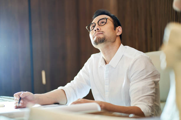 istock Asian bearded designer sitting, thinking and sketching ideas indoors 1310423801