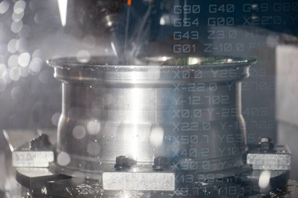 Modern CNC machine machining car alloy wheel with coolant. CNC programming code. Industrial manufacturing metalwork.
