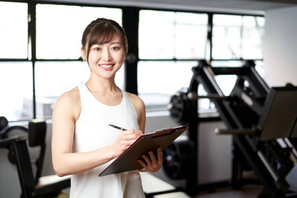 asian female trainer standing with a smile in the training gym - instructor exercising gym women imagens e fotografias de stock