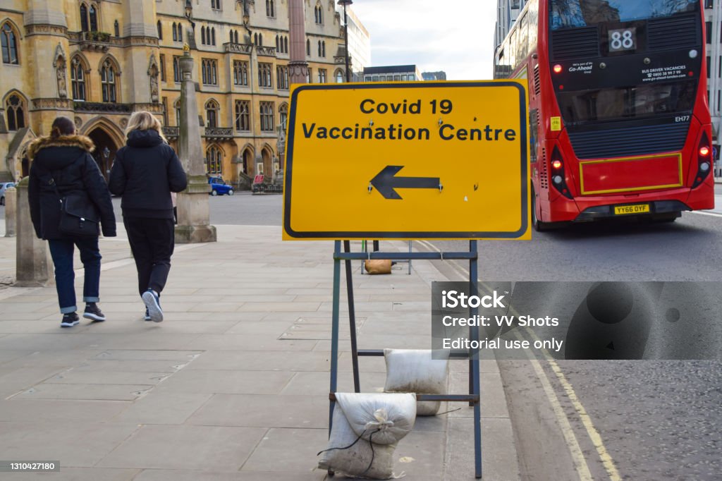 Covid-19 Vaccination Centre sign at Westminster Abbey, London, UK London, United Kingdom - March 19 2021: People walk past a Covid-19 Vaccination Centre sign outside Westminster Abbey. COVID-19 Vaccine Stock Photo