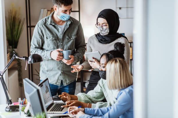 istock People with protective face masks working in office together 1310429227
