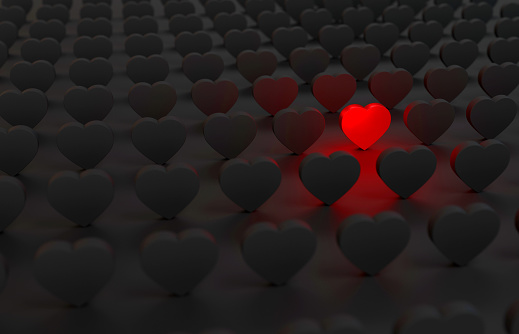 The Red Heart Shape between the Heart Shapes in the dark. Standing Out From The Crowd Concept.