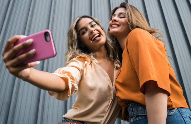 istock Two friends taking selfie with phone outdoors. 1310435083