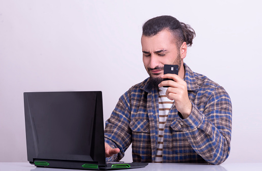 Young man who made online purchases with credit card and laptop is frustrated.