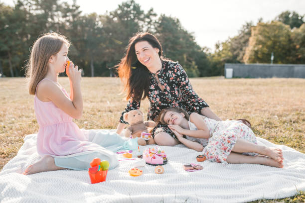 istock Mother two daughters and teddy bear having a tea party in park 1310436128