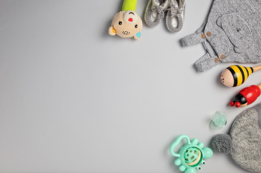 Baby toys and clothing on gray background. Flat lay concept.