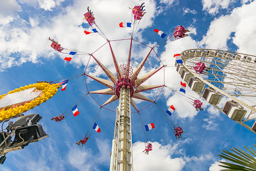 Carousel of the Fete des Tuileries, the Tuileries Fair, the second largest carnival in Paris after the Foire du Trone, with people  having fun a summer day with blue sky