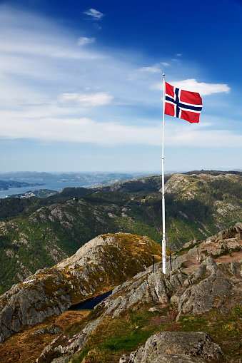 The flag of Norway waves in the wind on the hillside above the town of Bergen.