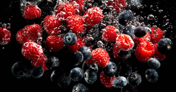 istock Blueberries and raspberries splashing into water with air bubbles and sinking on black 1310450351