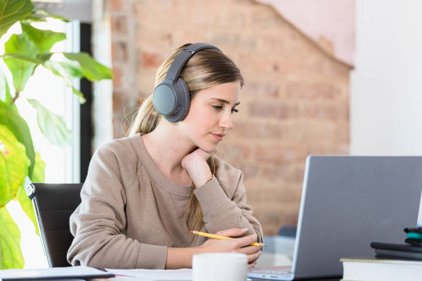 istock College student wears headphones while attending online class during COVID-19 1310450553