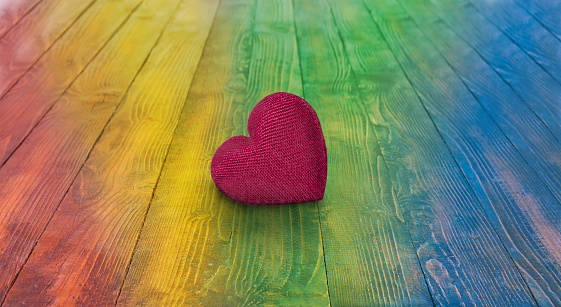 Heart symbol of love on a rainbow wooden background