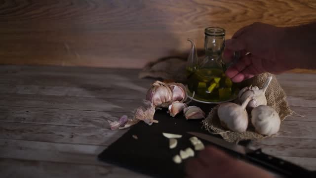 video of a person chopping garlic and putting it in olive oil to make an aromatic garlic oil as a condiment for food and natural therapies.