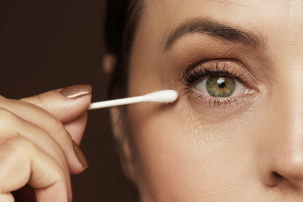 Female face and cotton swab. Hygiene or makeup corrections. Closeup of aged female face and cotton swab. Hygiene or makeup corrections. cotton swab stock pictures, royalty-free photos & images