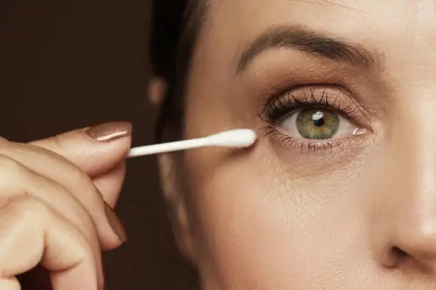 Closeup of aged female face and cotton swab. Hygiene or makeup corrections.