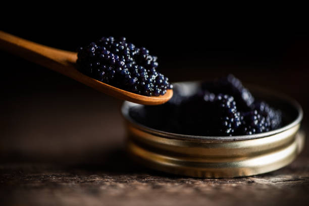 schwarzer klumpenfisch kaviar in einem kleinen topf und löffel - kaviar fotos stock-fotos und bilder
