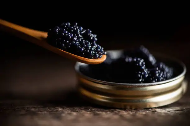 Black lumpfish caviar in a small pot and spoon close up