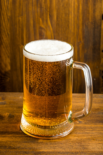 glass of beer with foam deposited on the wooden table