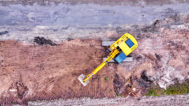 istock Excavator or earth mover digging a soil on a sideroad before laying new layer of the road. 1310460880