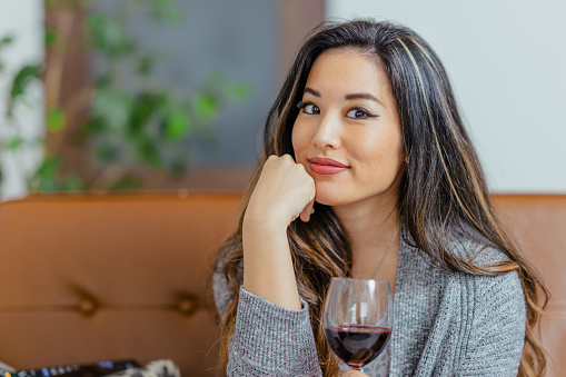 A portrait of a beautiful woman drinking red wine at home.