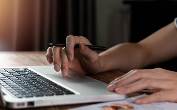 istock Male hand using laptop computer working on wooden table at home. Using laptop for searching web browsing, and having working workplace at home. 1310462256