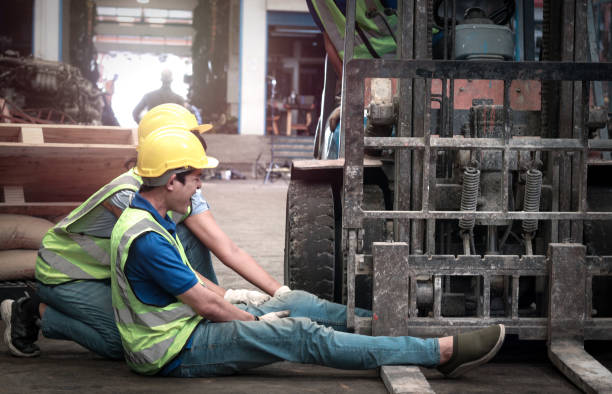 istock Accident at workplace, industrial engineer worker wearing helmet hit by forklift car at manufacturing plant factory construction site building, man leg stuck in forklift, colleague try to help him 1310463446