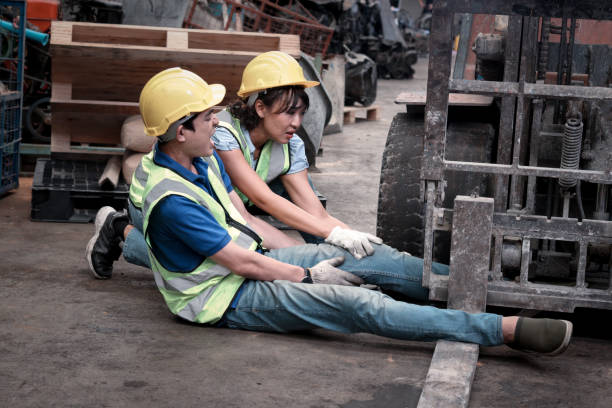 Accident at workplace, industrial engineer worker wearing helmet hit by forklift car at manufacturing plant factory construction site building, man leg stuck in forklift, colleague try to help him accidente en el lugar de trabajo, trabajador de ingeniería industrial con casco golpeado por carretilla elevadora en el edificio de construcción de la fábrica de fabricación, hombre pierna atrapada en la carretilla elevadora, colega tratar de ayudarle