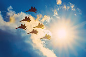 Group of fighter airplanes fly with the bright sun in the sky.