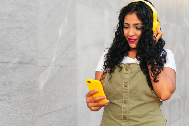 istock Young girl with curly hair using cell phone while standing upright 1310468472