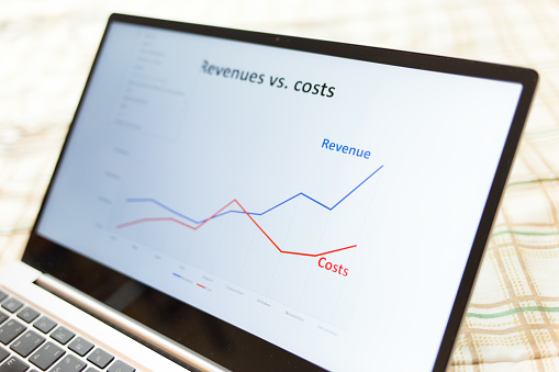 Screen of a laptop showing a graph of revenue and costs. Investment,  business and finance concept. Graph with lines showing financial growth.
