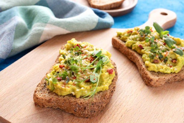 istock Two toasts with avocado, microgreens and hemp seeds on a wooden kitchen board 1310473674