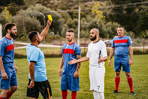 Soccer referee showing yellow card to soccer player.