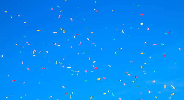 istock multicolored confetti on clear blue sky background. Concept of h 1310474053