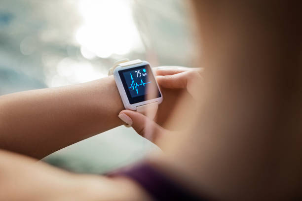 mujer mirando su reloj inteligente para un rastro de pulso - artículo médico fotografías e imágenes de stock