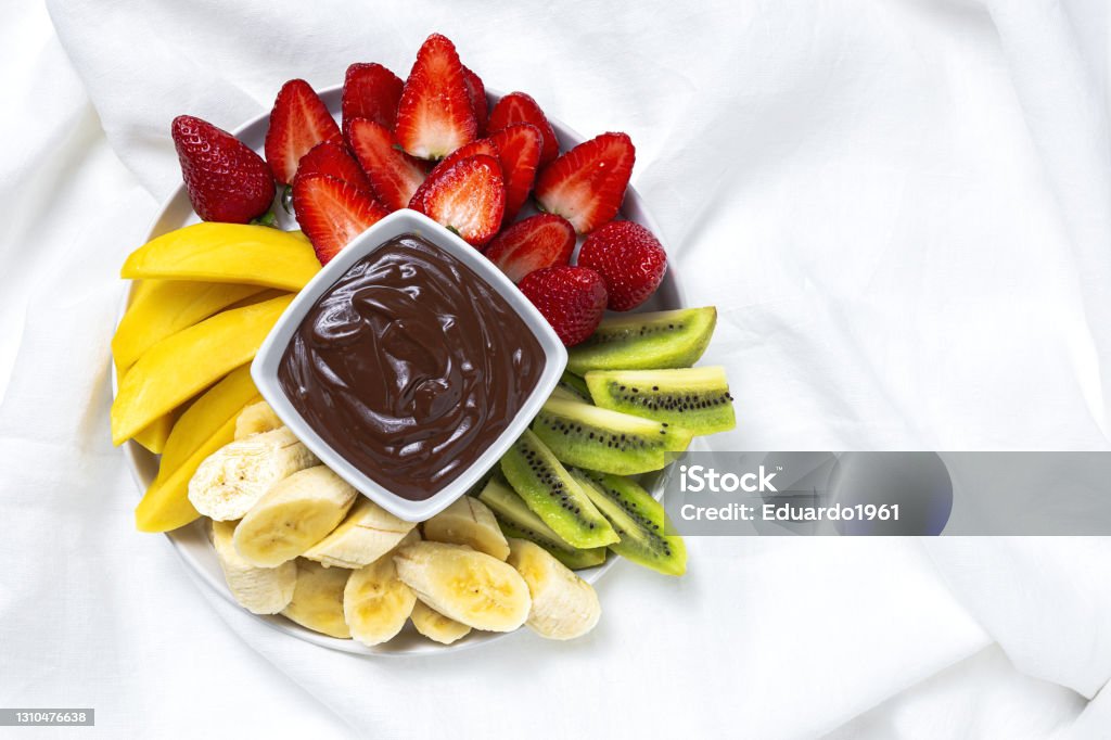 Dish of Fruits with chocolate ready to eat take away Dish of Fruits with chocolate ready to eat take away. Healthy food concept. Strawberries, mango, banana and kiwi Dark Chocolate Stock Photo