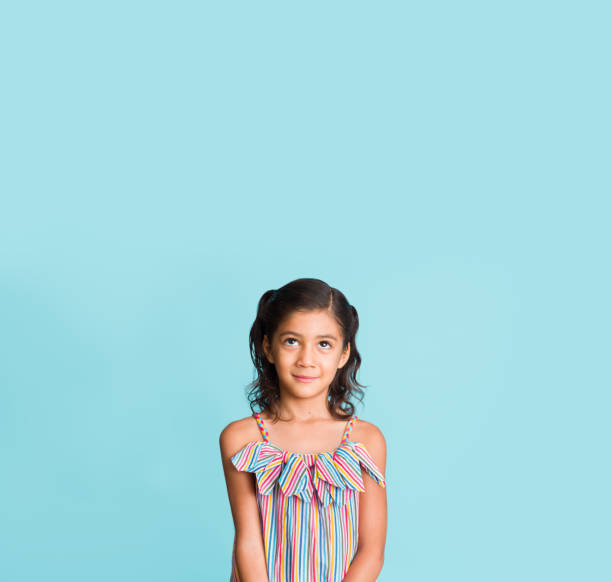 Studio shot of beautiful little girl looking up with copy space.