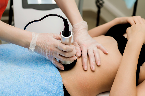 A woman in a beauty salon receives a vacuum abdominal massage, Hardware cosmetology. The cosmetologist works with the client
